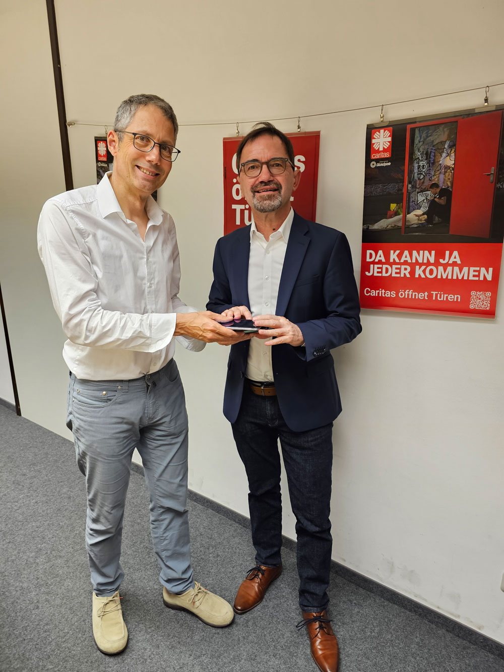 Michael Groß (li.) überreicht Alt-Smartphones an Michael Endres.